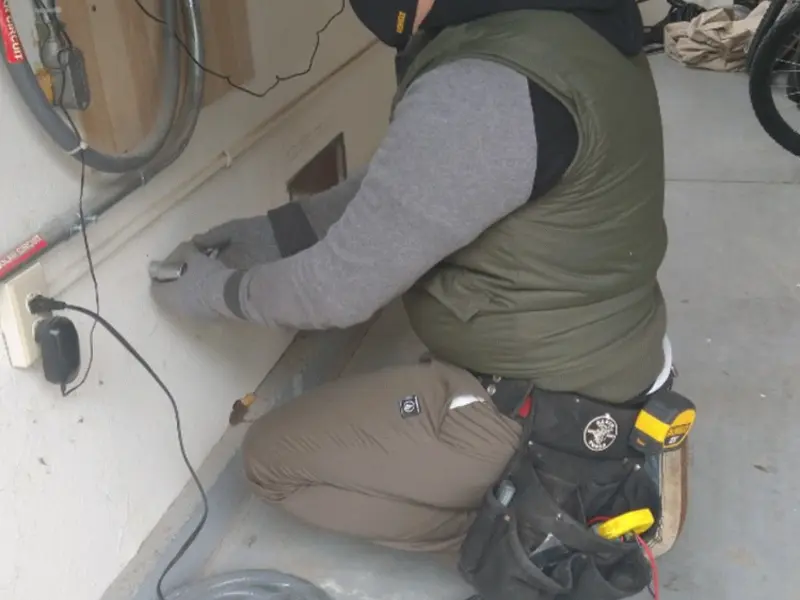 Electrician performing outlet wiring in a Bryan garage